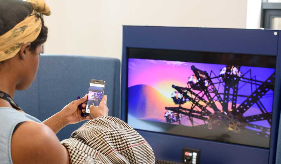 Student taking photo with her mobile phone of a computer screen displaying another student's work
