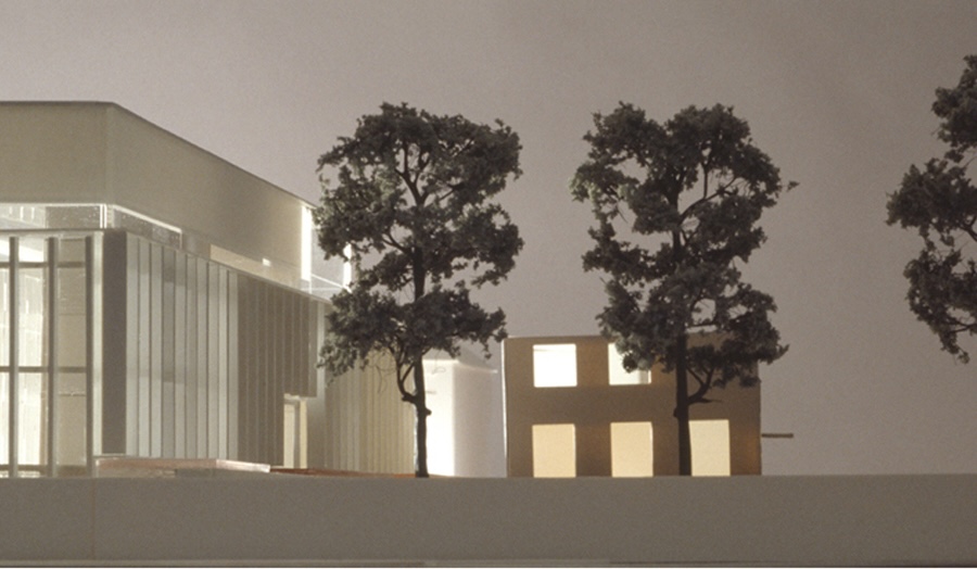 Architectural model showing a glass building beside a simpler structure with three detailed trees