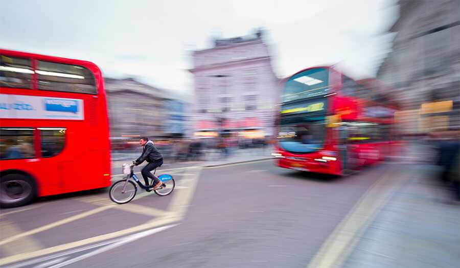 Red buses and a cyclist on a London road