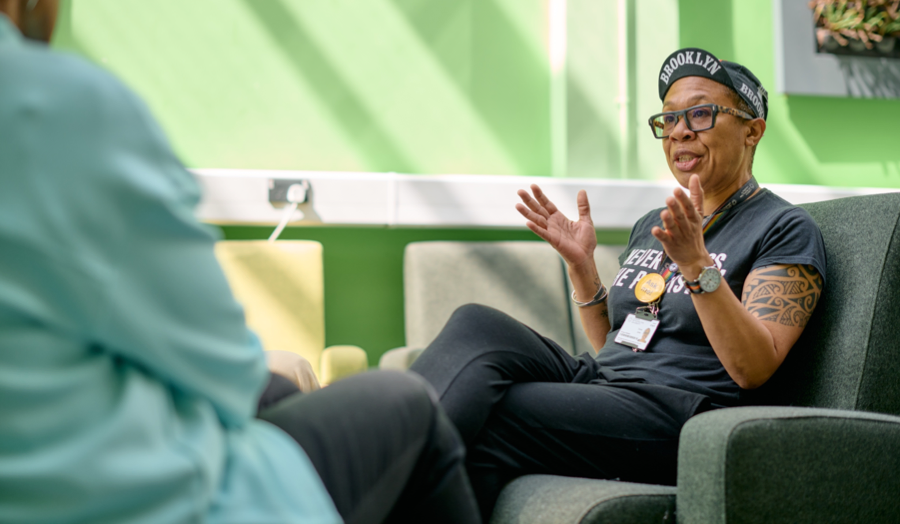 Staff member Donna Jones sitting on a chair in a green room talking to a colleague.