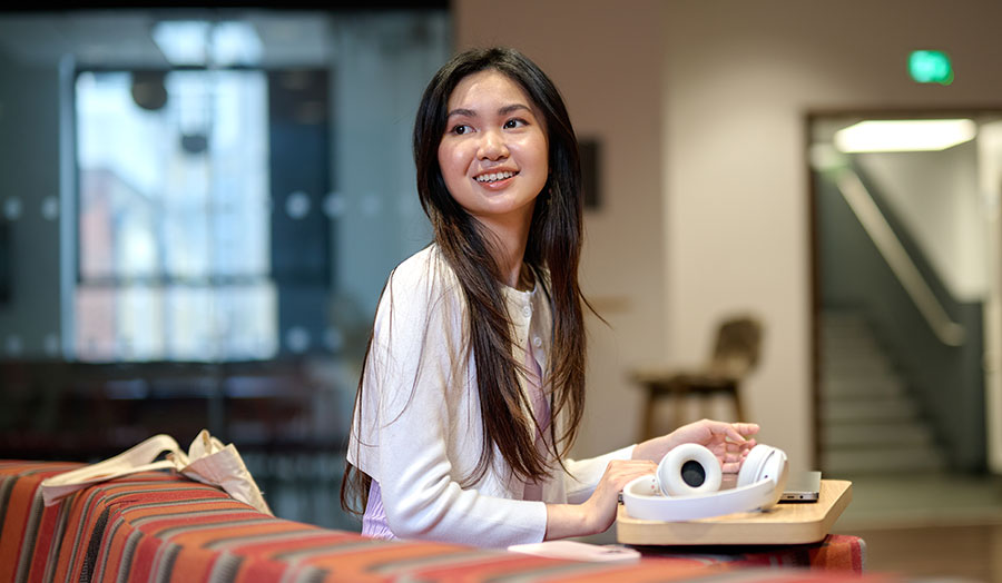 Socheata at Holloway campus, pictured smiling with headphones nearby