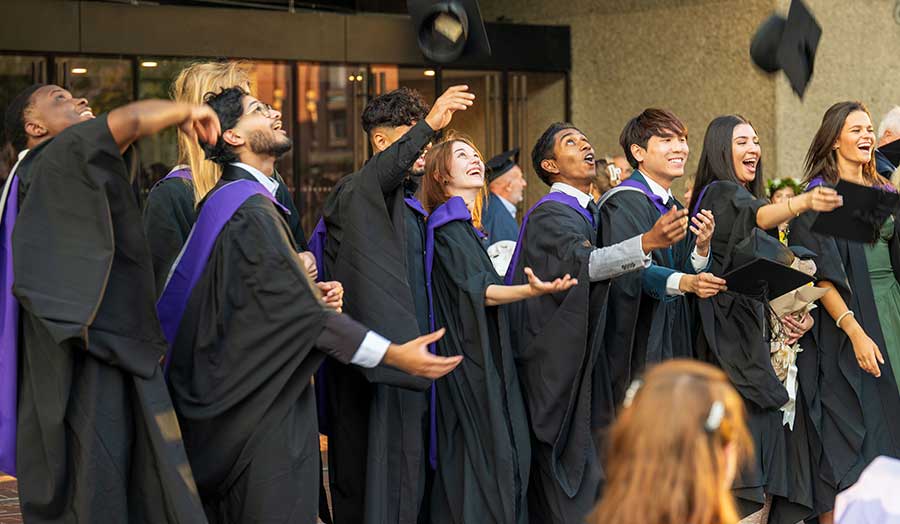 A group of students throw their caps in the air at graduation