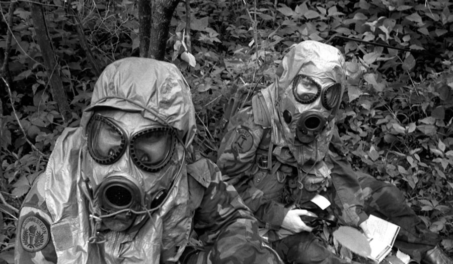 Two people fully geared with personal protective equipment walking in the forest