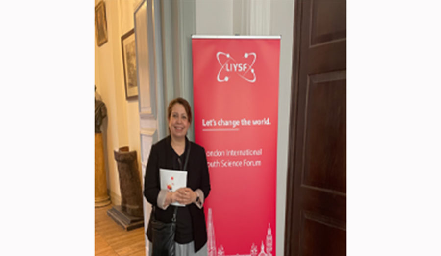 Dr Samireh Jorfi standing in front of the banner of the LIYSF event