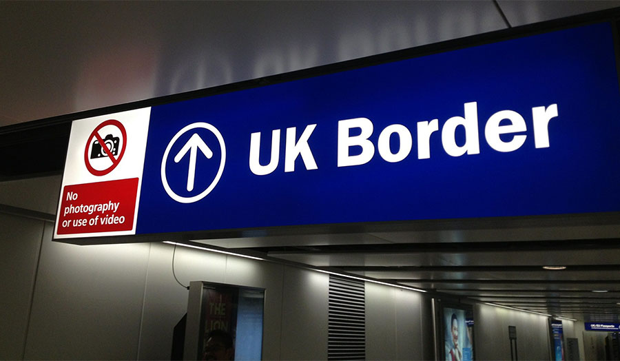 A blue and white sign at an airport, indicating the UK Border
