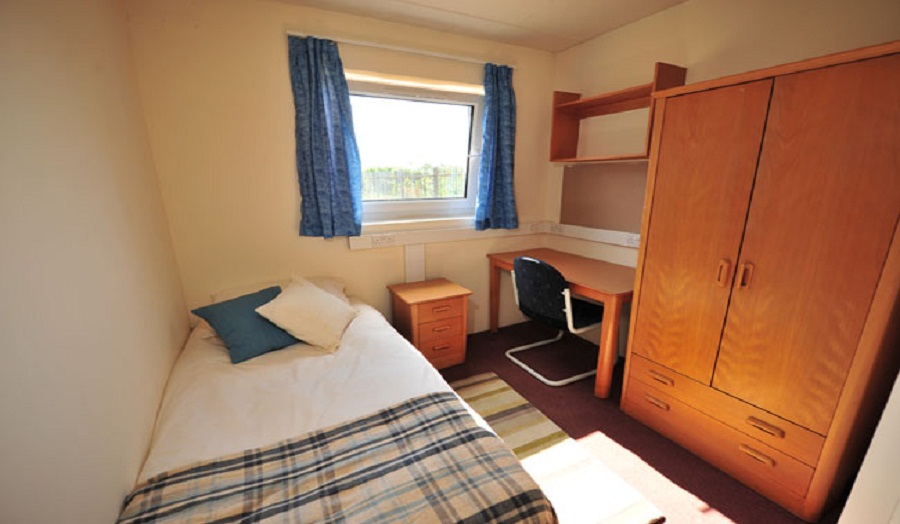 Photograph of a bedroom at Robbins Hall showing a single bed, desk and wardrobe.