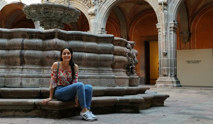 student Paulina sitting on a grand architectural fountain