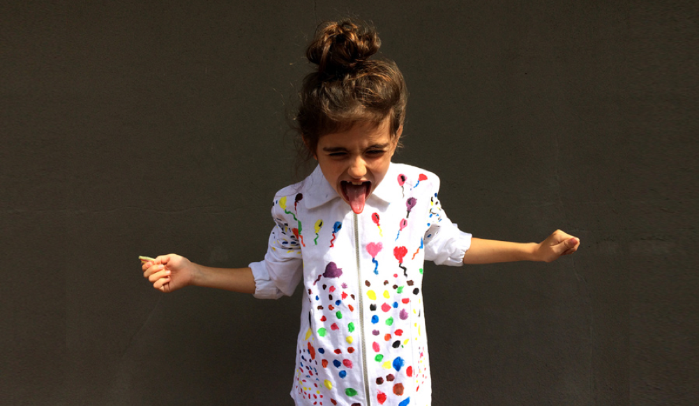 A child sticking her tongue out and wearing a colourful shirt